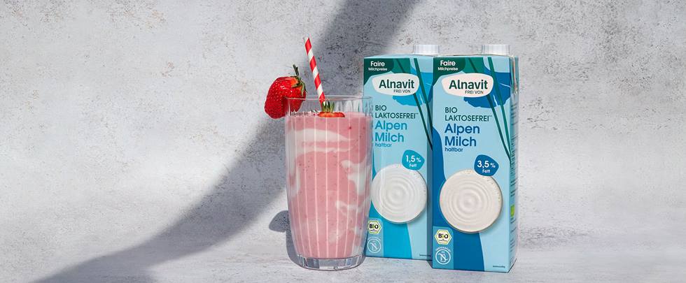 Laktosefreier Erdbeer-Milchshake Alnavit: Erdbeershake im Glas mit Milchpackungen